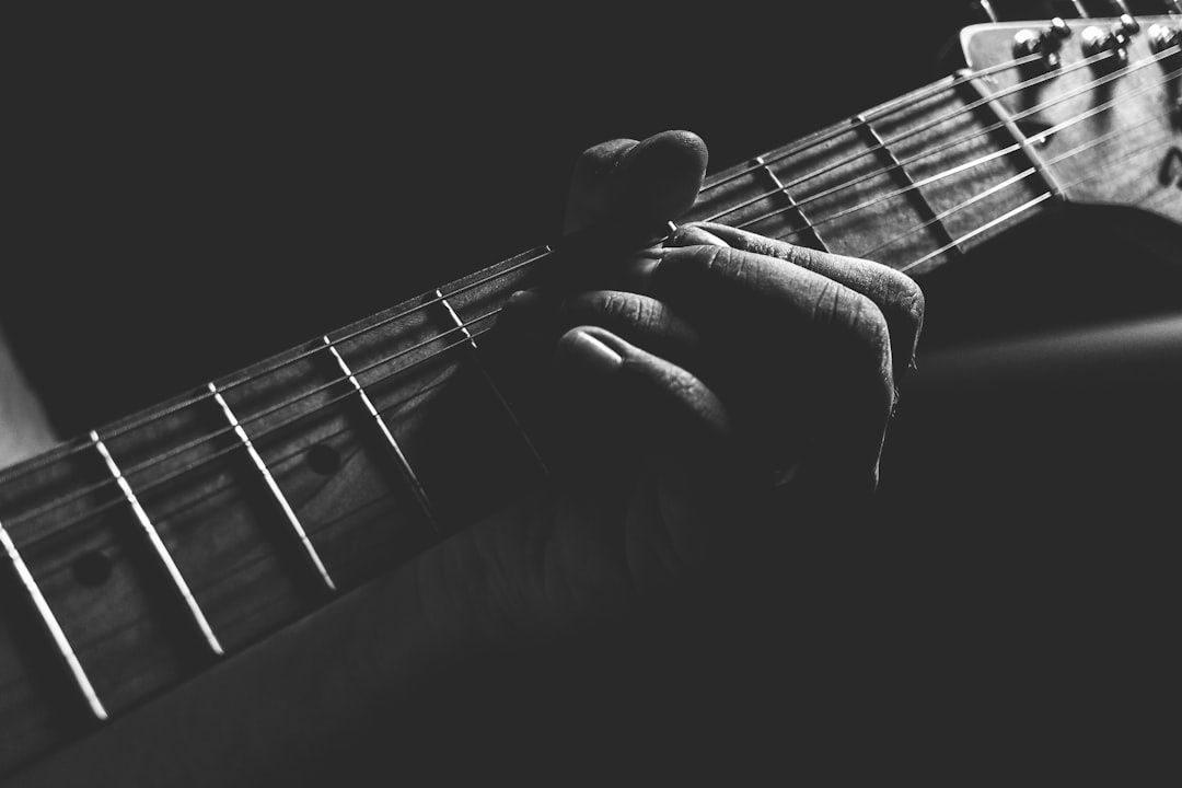 Black-and-white close-up of a hand forming a chord on an acoustic guitar