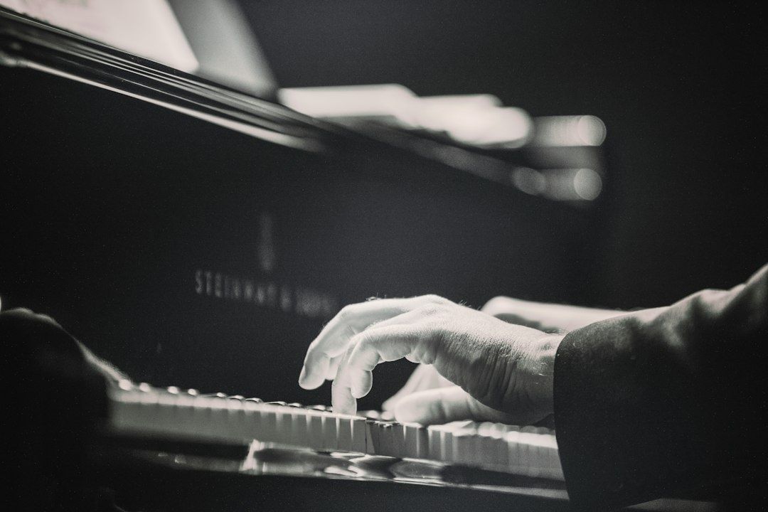 Close-up of hands playing piano keys beneath a blurred music stand