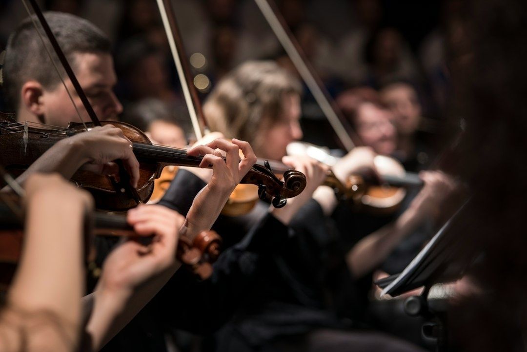 String players bow violins together in a softly lit ensemble
